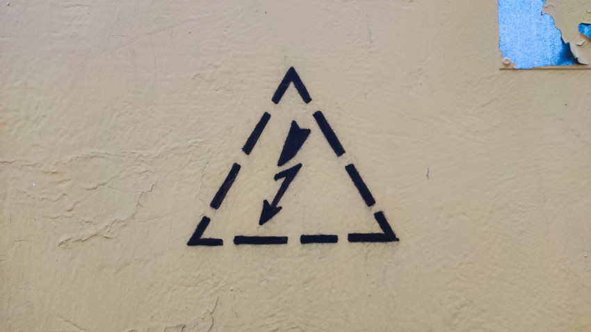 Предупреждающий знак электрической опасности на жёлтой поверхности