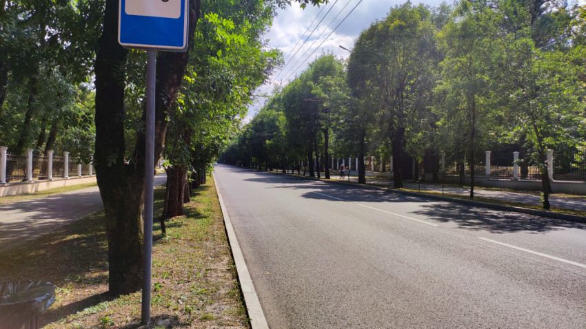 Пустая аллея проезжей части у остановочного знака в Городском парке Нальчика