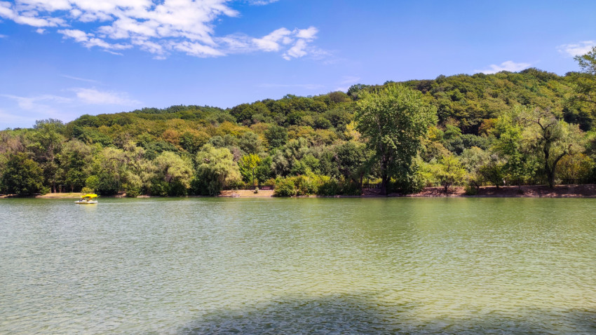Озеро «Трек» с катамараном у лесистого склона в Нальчике