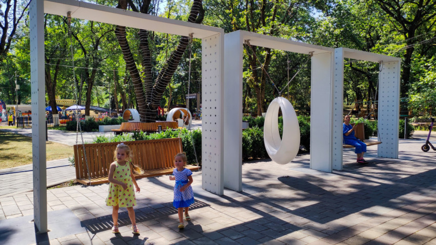 Детская зона отдыха с подвесными качелями и белыми рамами в парке