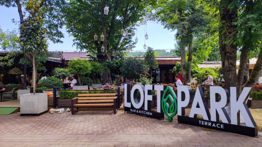 Вывеска LOFT PARK у летней террасы среди деревьев в Городском парке Нальчика