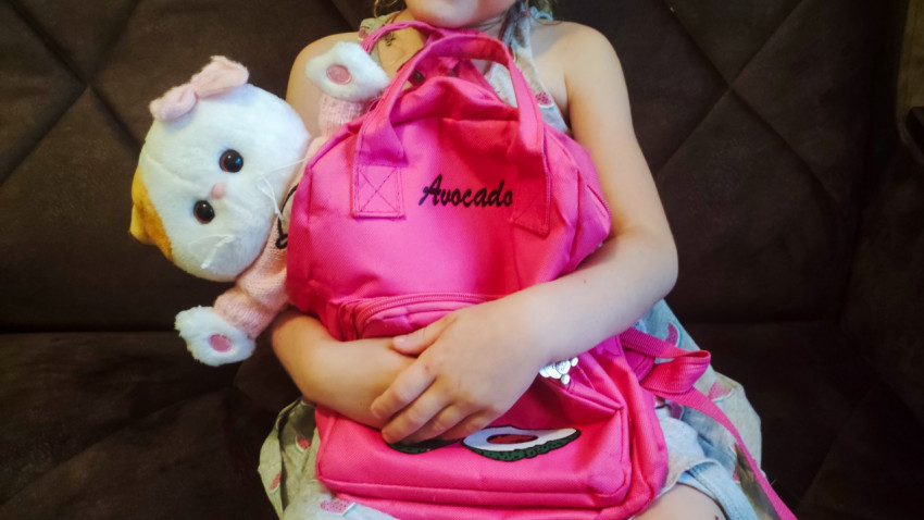 Ребёнок держит розовый рюкзак Avocado и мягкую игрушку
