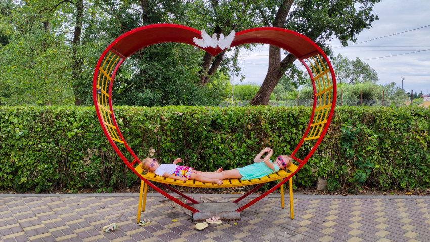 Дети отдыхают на круглой качели в форме сердца в Комсомольском парке Прохладного