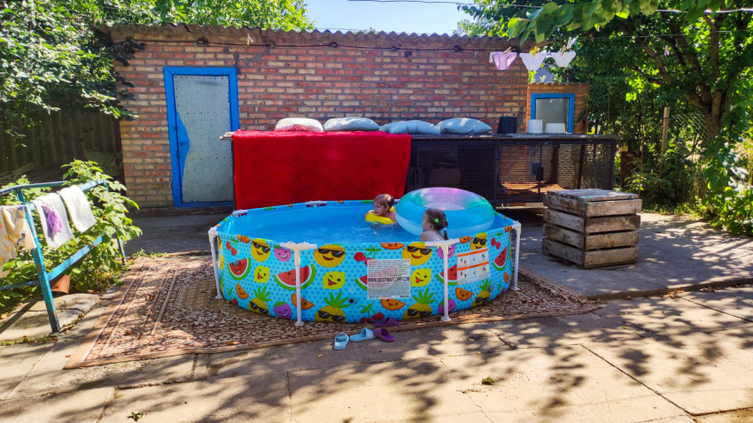 Дети купаются в каркасном бассейне во дворе частного дома