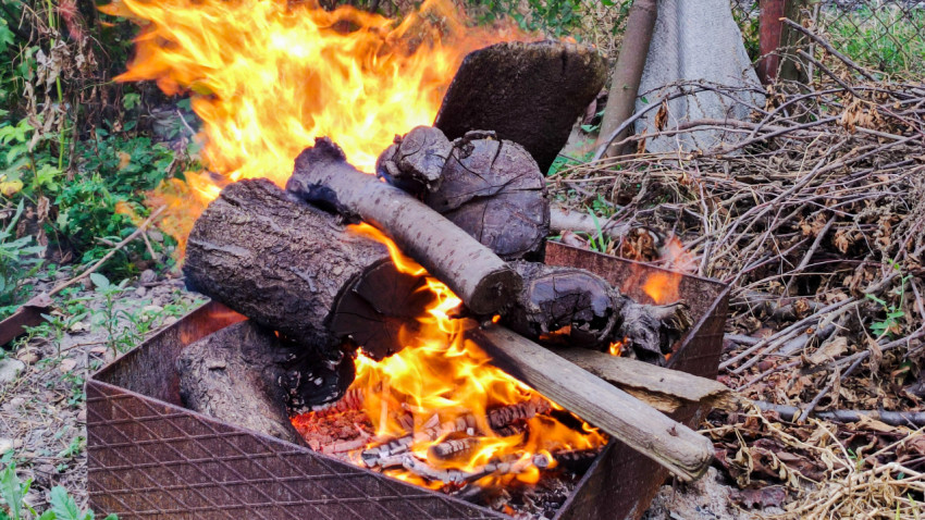 Сильное пламя за поленьями в металлической жаровне