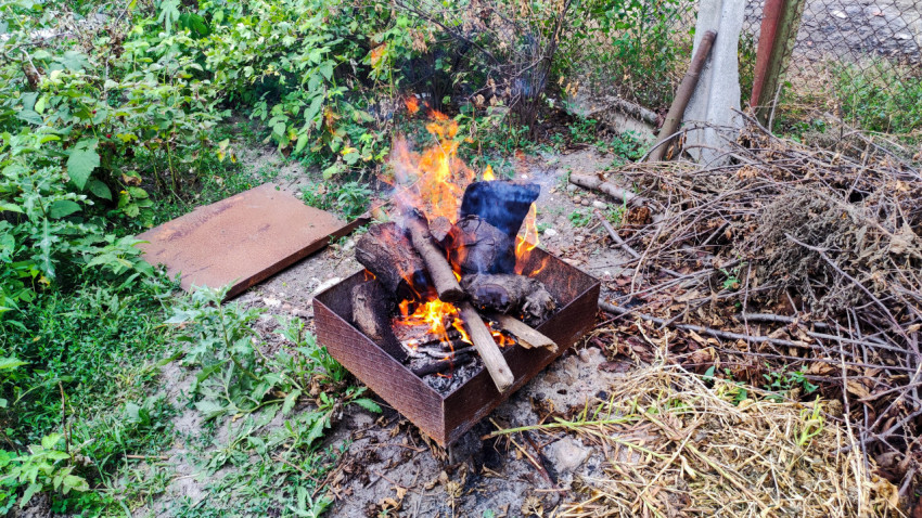Костёр в жаровне среди зелени и веток