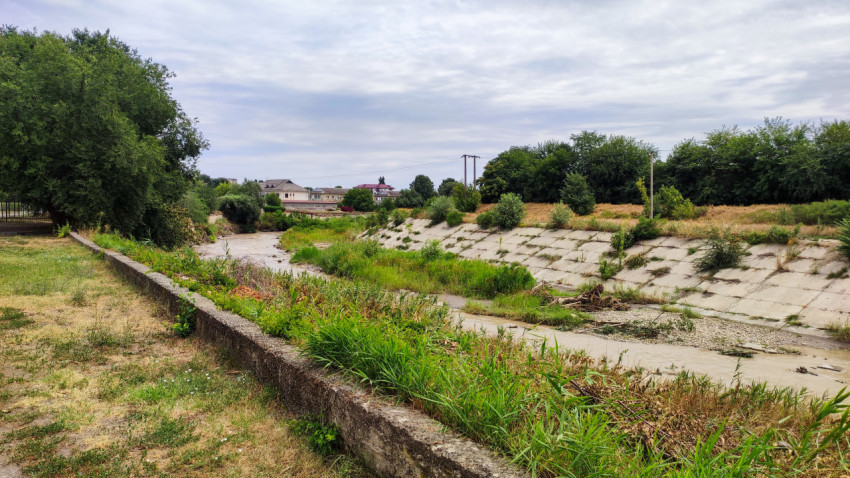 Панорама русла реки Малка с бетонными берегами и зелёными отмелями