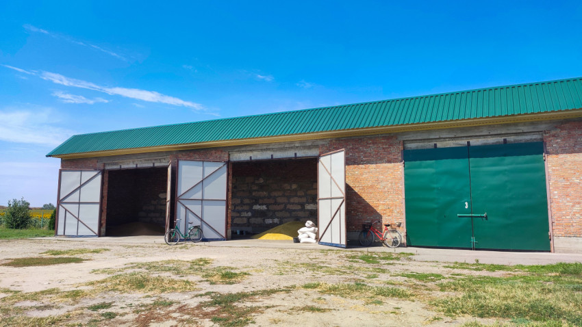 Сельскохозяйственный склад с открытыми воротами и зелёной крышей