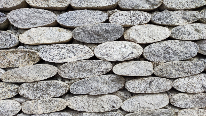Текстура стены из овальных гранитных камней крупным планом