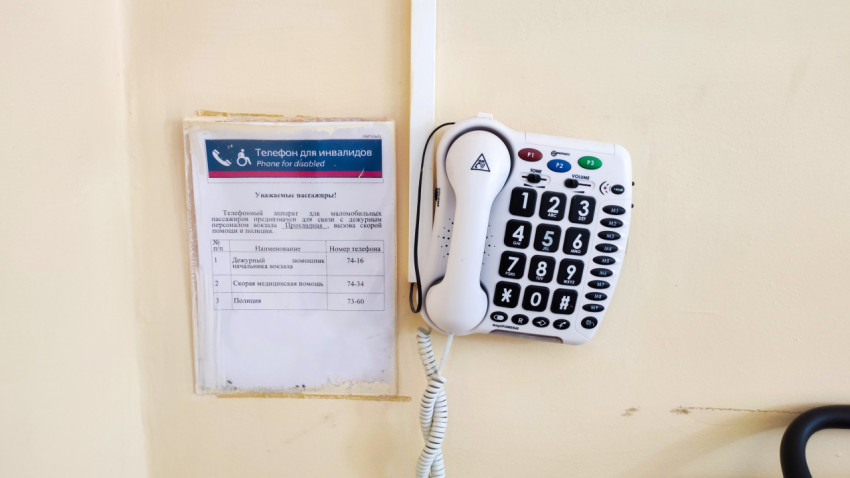 Настенный телефон с крупными кнопками рядом с табличкой «Телефон для инвалидов»