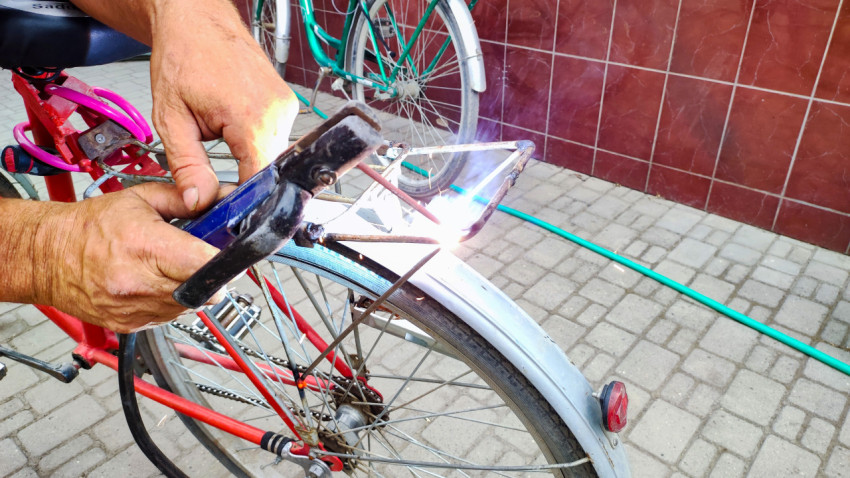 Сварка стойки багажника велосипеда у серебристого крыла