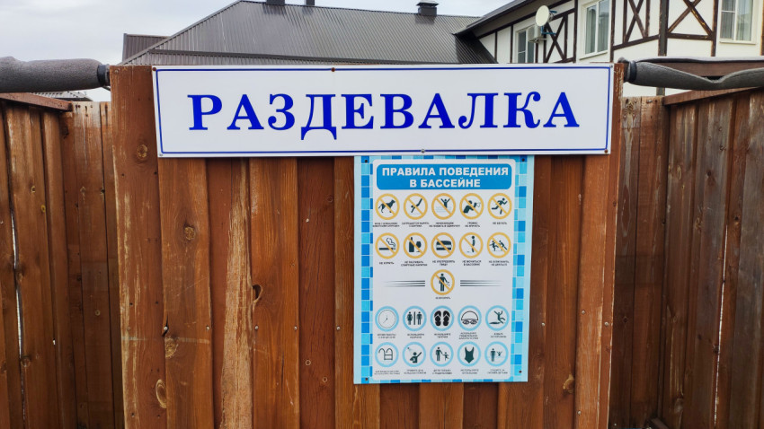 Табличка «Раздевалка» и правила поведения в бассейне на деревянном заборе
