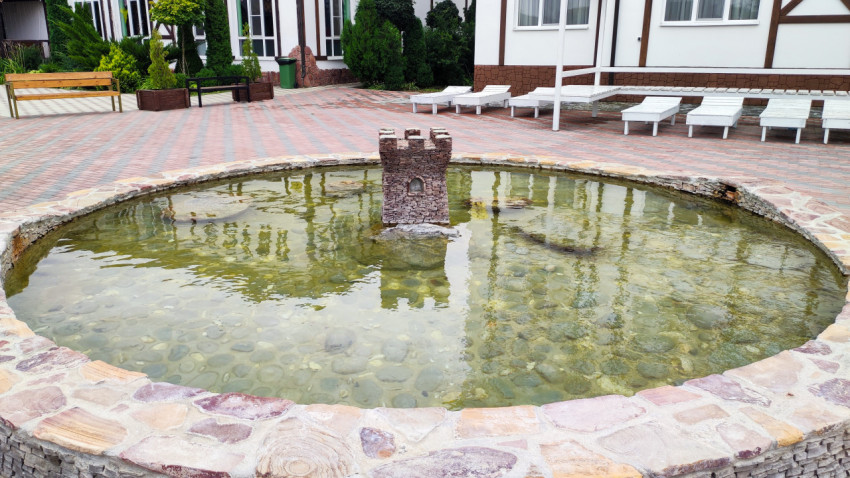 Круглый декоративный водоём с каменной башенкой во дворе комплекса