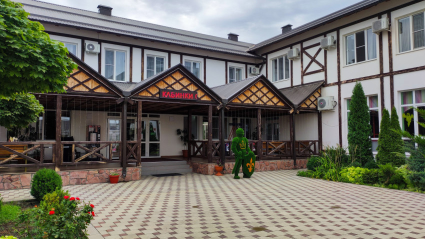 Вход в здание с вывеской «КАБИНКИ» и топиарной фигурой рыцаря