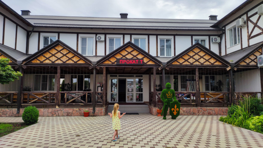 Вход с вывеской «ПРОКАТ» и декоративной фигурой рыцаря во дворе комплекса