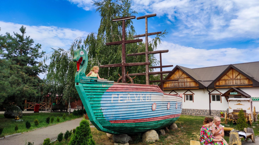 Декоративный деревянный корабль с мачтами служит игровой площадкой у входа на территорию комплекса