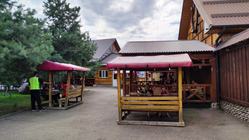 Деревянные беседки с лавками под тентами образуют зону питания у туристического комплекса