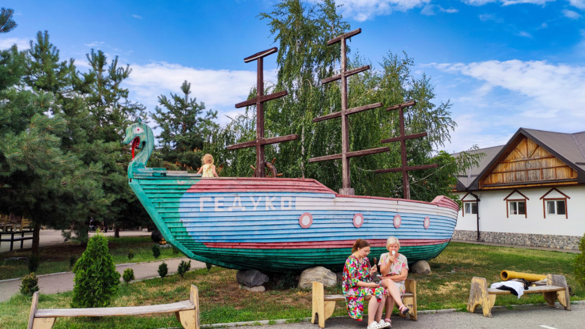 Большой раскрашенный корабль из дерева стоит рядом с лавками в зоне отдыха комплекса