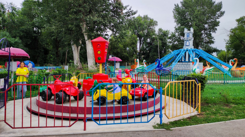 Детская карусель с машинками и светофором работает в парке аттракционов