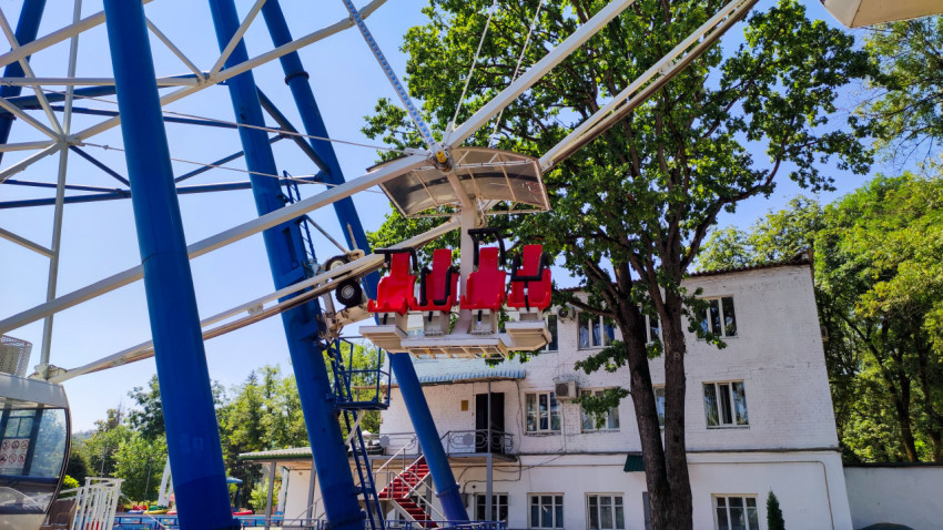 Подвесные кресла аттракциона на фоне опор колеса обозрения