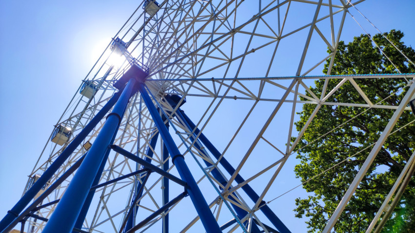 Опоры и спицы колеса обозрения в контровом свете с солнечным бликом