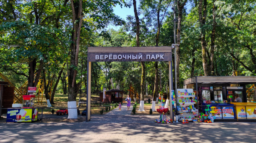 Входная арка с надписью «Верёвочный парк» на аллее среди деревьев