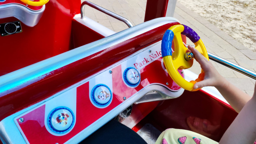 Рука ребёнка держит руль детского аттракциона крупным планом в Городском парке Нальчика