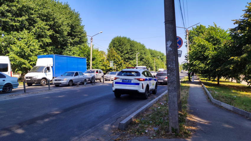 Служебный автомобиль с проблесковыми маячками припаркован у оживлённой городской дороги