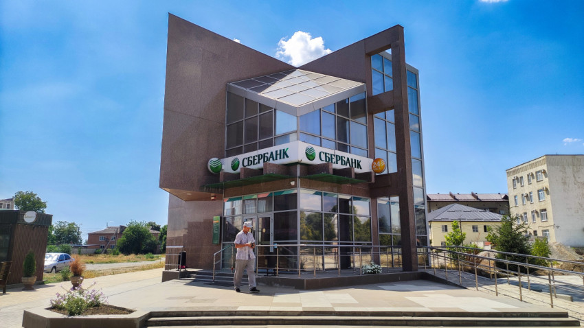 Вход в отделение Сбербанка с вывеской и табличкой «24 часа»