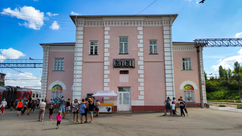 Пассажиры у вокзала «Елец» рядом с поездом РЖД на солнечном перроне