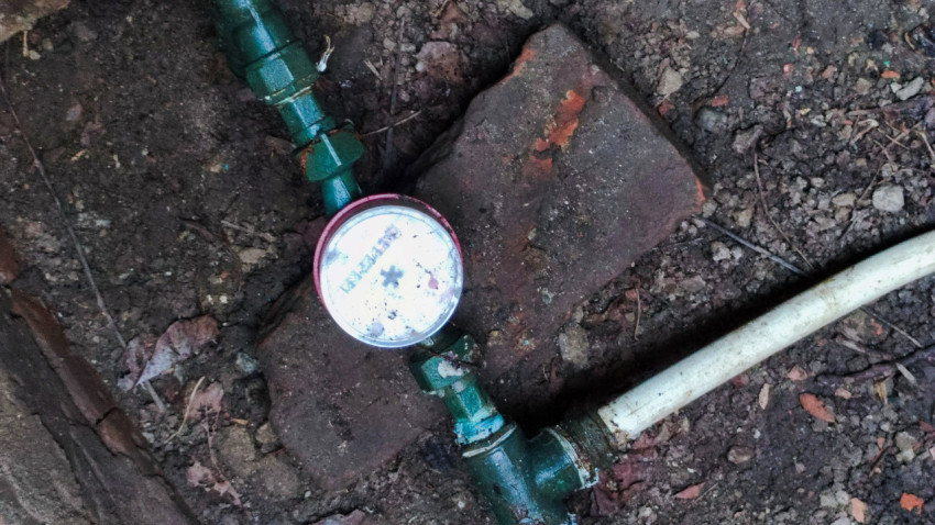 Крупный план водосчётчика на трубе в ревизионной яме