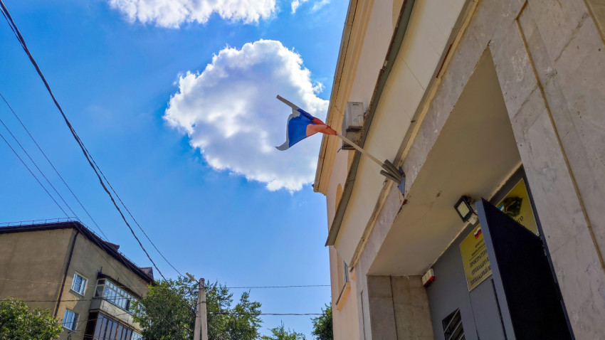 Фасад административного здания с флагом России на фоне облачного неба