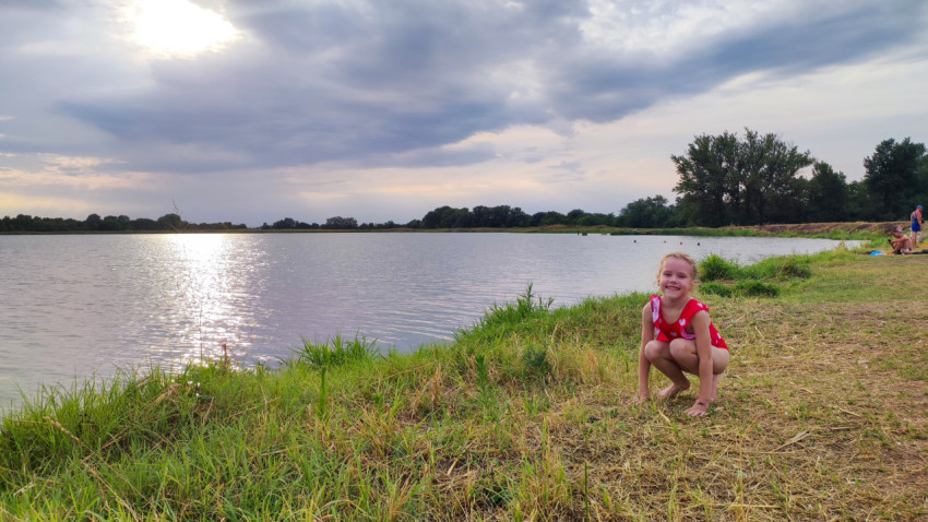 Девочка у берега озера в красном купальнике