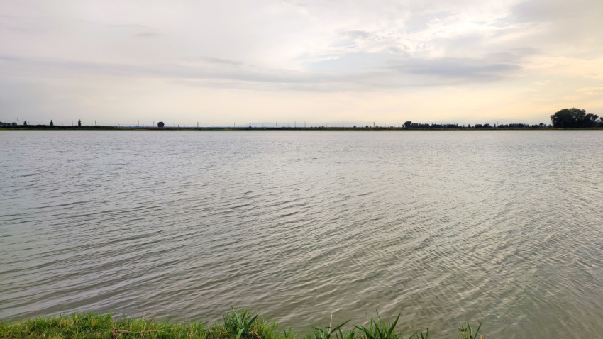 Рябь на воде и дальняя линия берега под светлым небом