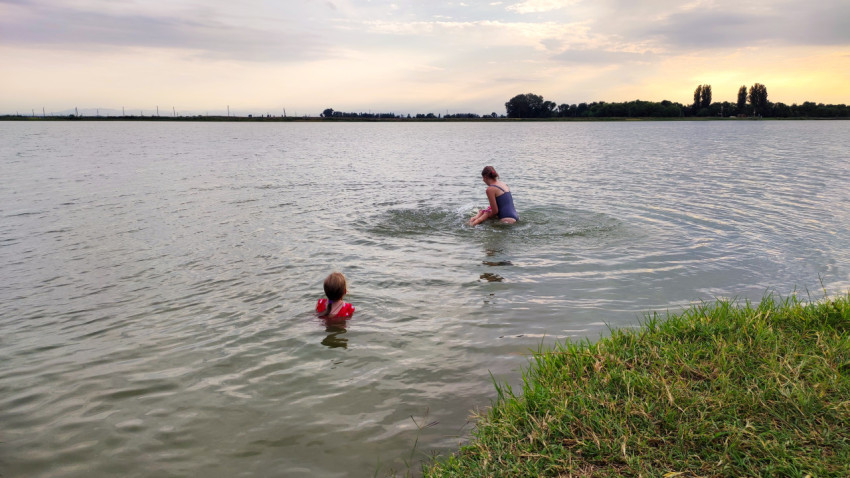 Женщина и ребёнок купаются в озере у травянистого берега