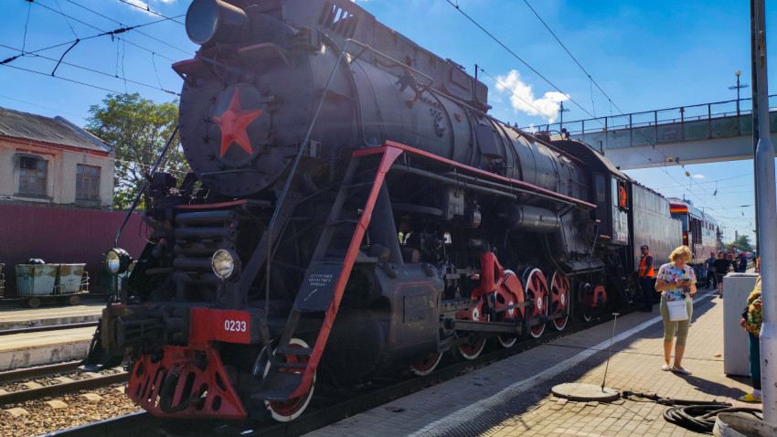 Боковой вид паровоза ЛВ-0233 с ходовой частью и красными колёсами у платформы