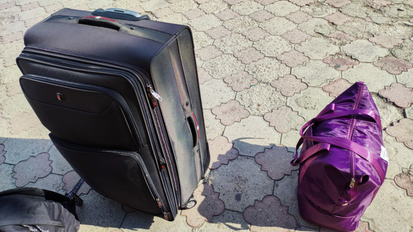 Чемодан на колёсах и дорожная сумка на тротуарной плитке перед поездкой