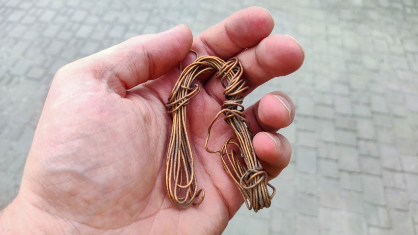 Связка медной проволоки в руке на фоне тротуарной плитки
