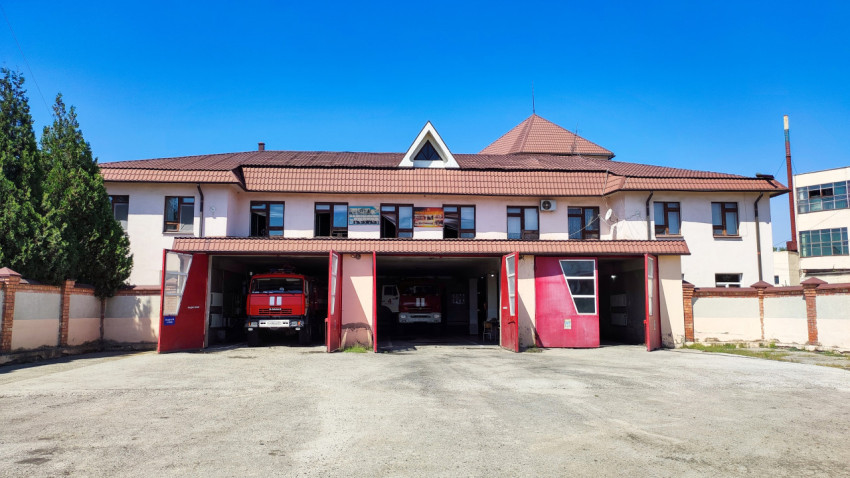 Пожарная часть с открытыми воротами и пожарными автомобилями в боксах