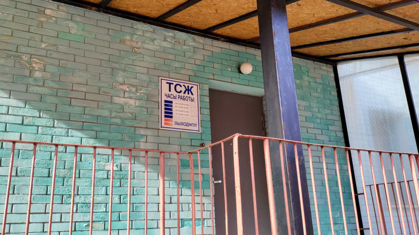 Вход в офис ТСЖ с графиком работы на кирпичной стене