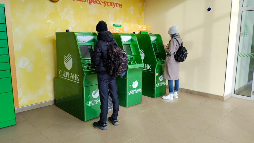 Люди используют банкоматы Сбербанка в помещении