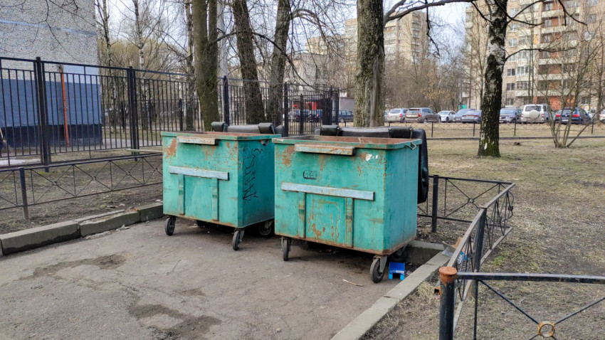 Два мусорных контейнера во дворе многоэтажного жилого дома