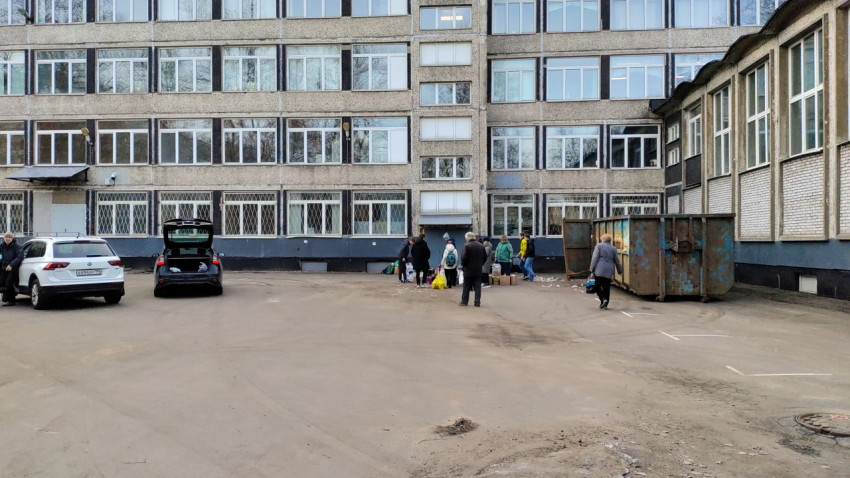 Группа людей сдаёт макулатуру возле школы