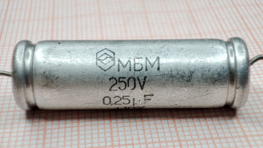 Конденсатор МБМ 250В 0.25мкФ на фоне миллиметровой бумаги крупным планом