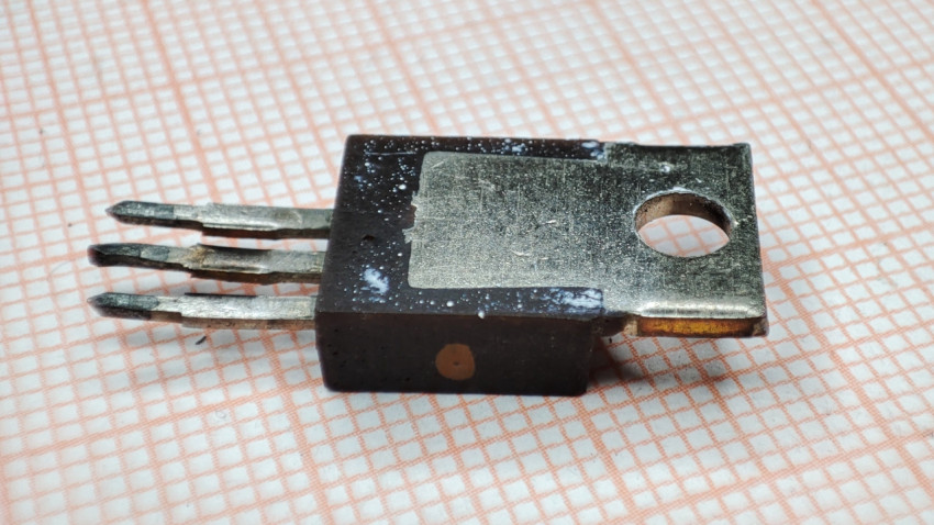 Транзистор КТ805ИМ в пластмассовом корпусе крупным планом на фоне бумаги