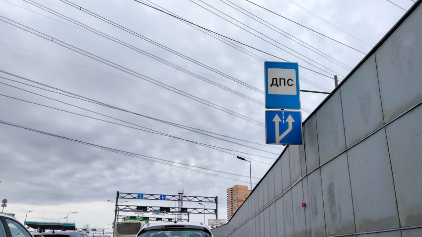 Дорожные указатели и автомобили на участке городской магистрали