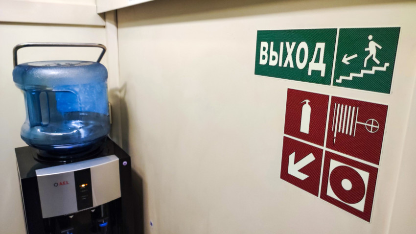 Кулер с водой рядом с указателем на стене
