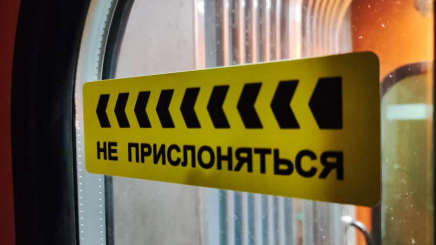 Желтый знак «Не прислоняться» на двери поезда