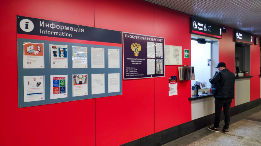 Мужчина покупает билеты на поезд в кассе