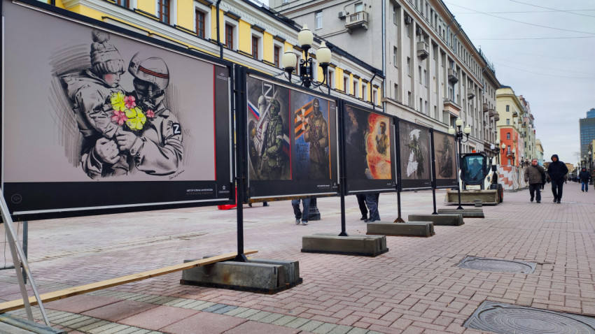 Прохожие идут мимо фотовыставки на Арбате